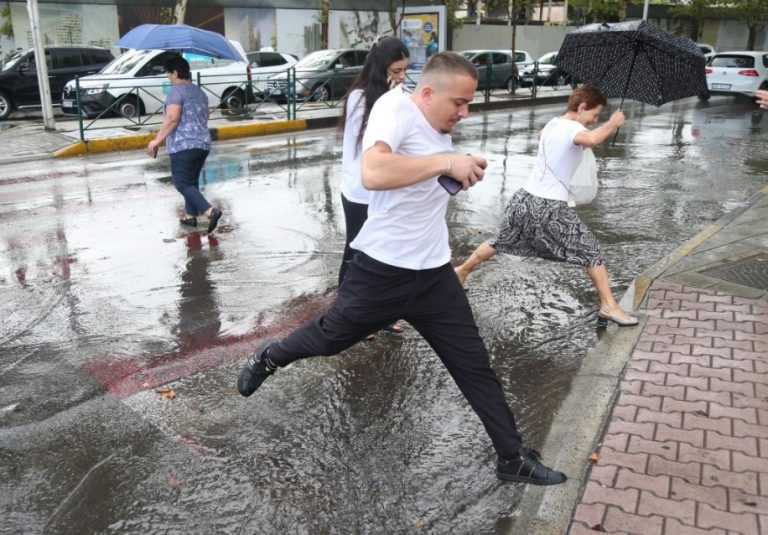 FOTO/ Njerëz që kapërcejnë rrugët e mbushura plot me ujë, shiu “pushton” Tiranën